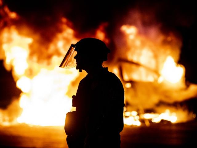 Police stands guard as Austin Fire Department put out a car fire under Interstate 35 freeway in Austin Texas, Saturday, May 30, 2020 (Ricardo B. Brazziell/Austin American-Statesman via AP)