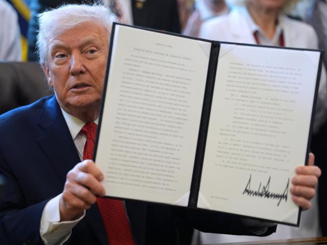 President Donald Trump displays an executive order reclassifying marijuana as a less dangerous drug in the Oval Office of the White House, Thursday, Dec. 18, 2025, in Washington. (AP Photo/Evan Vucci)