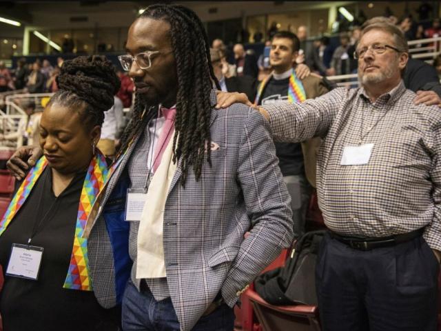 Adama Brown-Hathasway, left, The Rev. Dr. Jay Williams, both from Boston, and Ric Holladay of Kentucky join in prayer during the 2019 Special Session of the General Conference of The United Methodist Church in St. Louis, Mo. (AP Photo/Sid Hastings)
