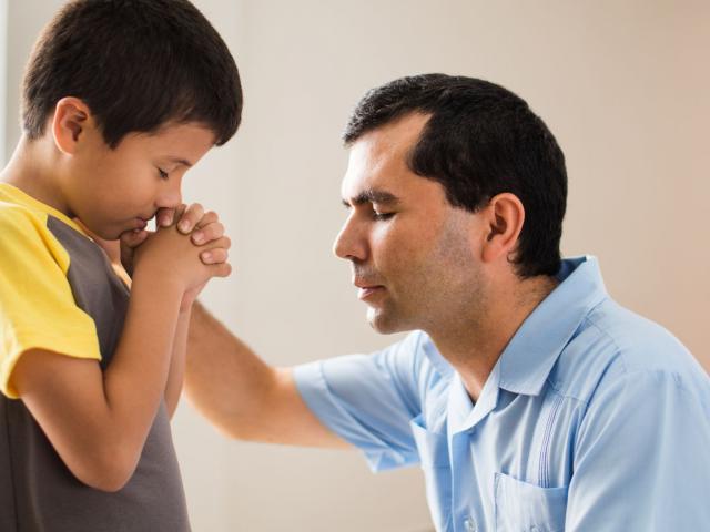 a father praying with his son