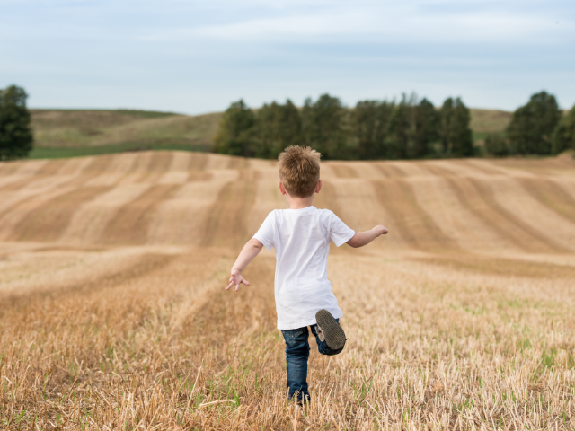 little boy running in a farming field
