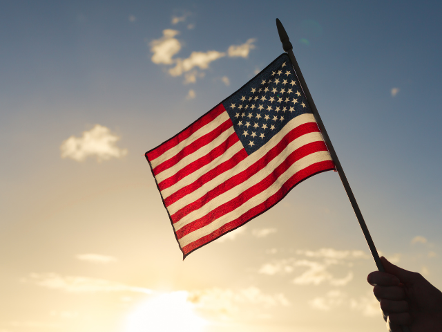 American flag held up with blue sky in the background