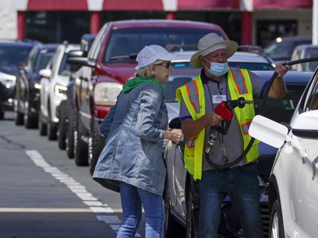A customer helps pumping gas at Costco, as other wait in line, on Tuesday, May 11, 2021, in Charlotte, N.C. (AP Photo/Chris Carlson)
