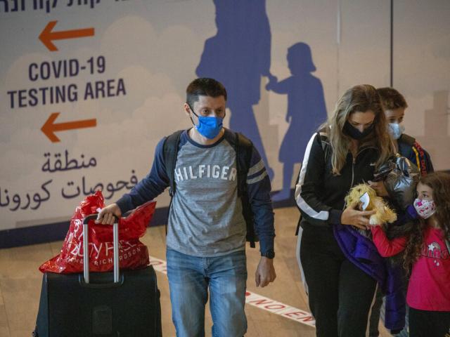 Travelers wearing protective face masks arrive at the Ben Gurion Airport near Tel Aviv, Israel, Sunday, Nov. 28, 2021. (AP Photo/Ariel Schalit)
