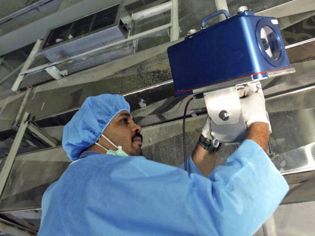 An inspector of the International Atomic Energy Agency sets up surveillance equipment, at the Uranium Conversion Facility of Iran, just outside the city of Isfahan, Iran, Aug. 8, 2005. (AP Photo/Mehdi Ghasemi, ISNA, File )