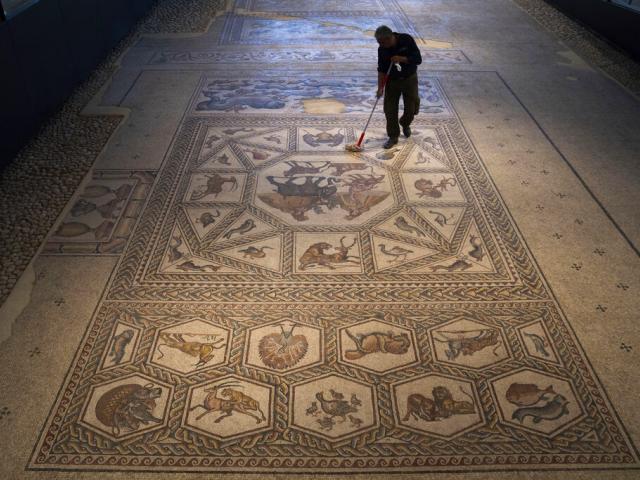 A worker cleans a restored Roman-era mosaic ahead of its display in its hometown ahead of the inauguration of the Shelby White &amp; Leon Levy Lod Mosaic Archaeological Center, in Lod, central Israel, Thursday, June 23, 2022. (AP Photo)