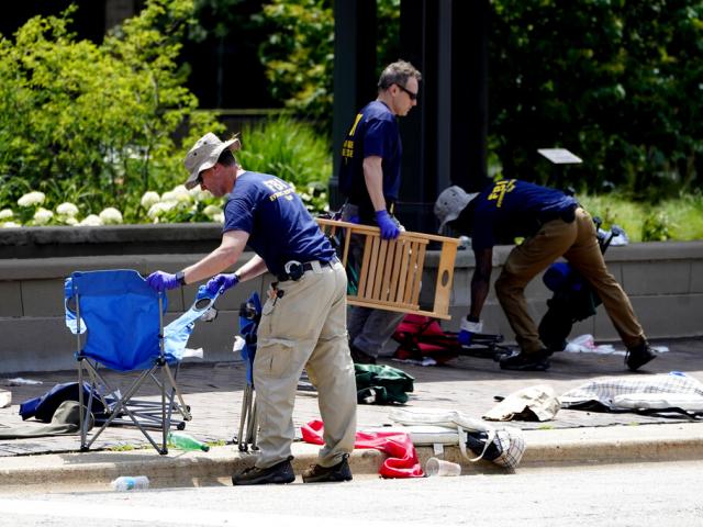 Members of the FBI&#039;s Evidence Response Team Unit investigate on Central Avenue near Green Bay Road in downtown Highland Park, Ill. (AP Photo/Charles Rex Arbogast)