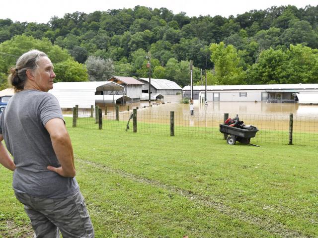 Bonnie Combs stands by and watches her property become covered by the North Fork of the Kentucky River in Jackson, Ky., Thursday, July 28, 2022. (AP Photo/Timothy D. Easley)