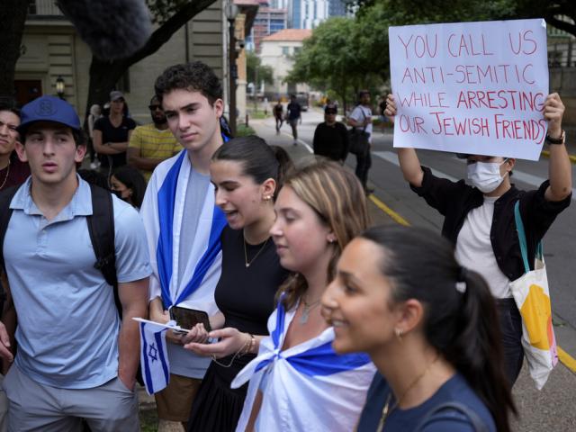 A Pro-Palestinian protester holds up a sign as Jewish students talk to the media following on campus at the University of Texas at Austin, Tuesday, April 30, 2024, in Austin, Texas. (AP Photo/Eric Gay)