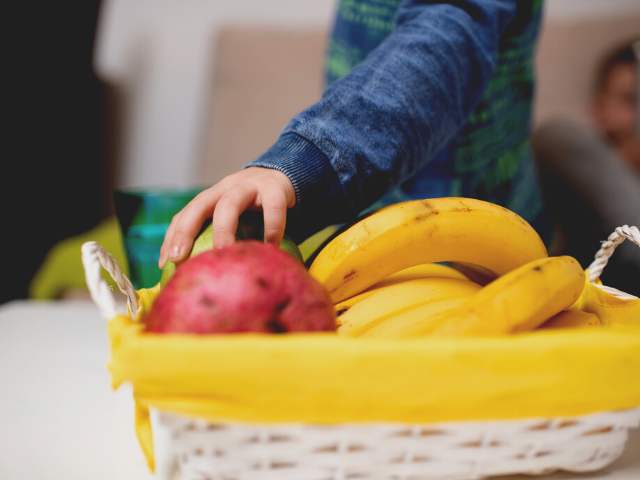 young person getting fruit from a basket