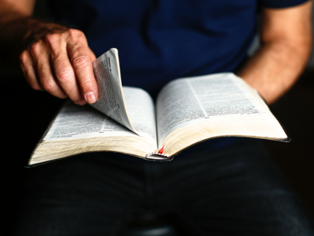 man turning pages of a Bible