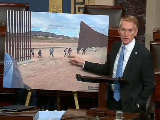 Sen. James Lankford shows the Senate photos of migrants streaming through gaps in the border fence.