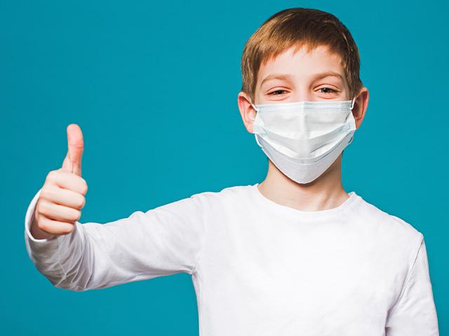 Boy in surgical mask smiling