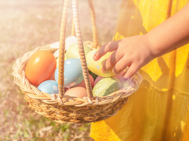 little girl carrying a basket of colored eggs