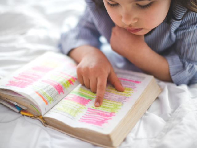 child reading a highlighted Bible