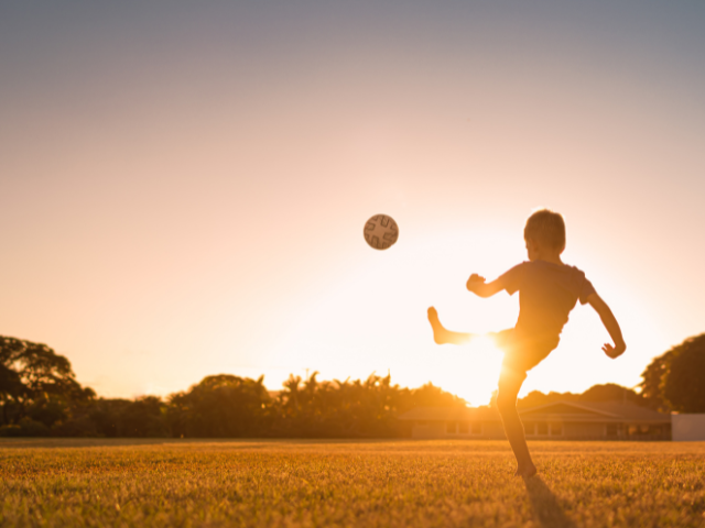 child kicking a soccer ball