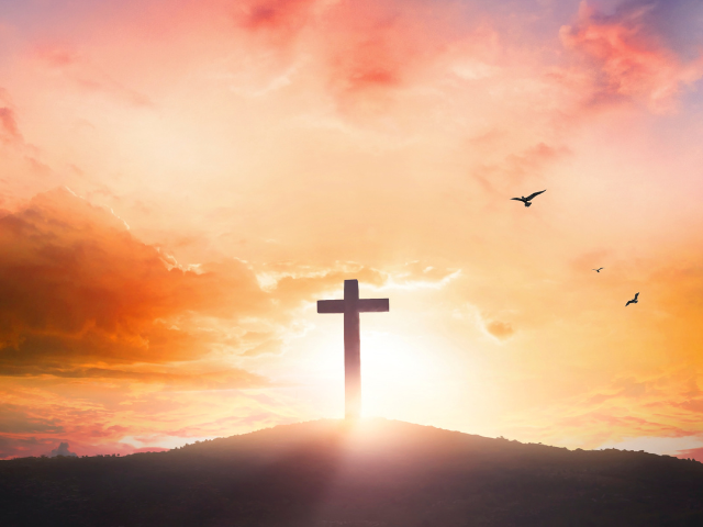 cross on a hill with a colorful sky background