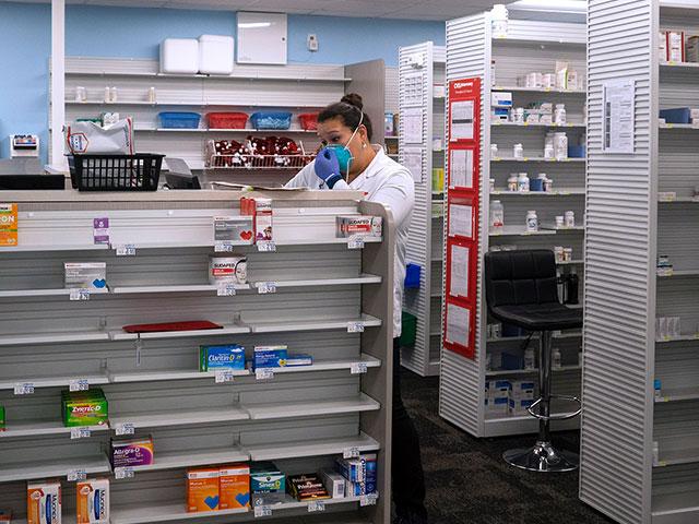Pharmacist Evelyn Kim, wears a mask and gloves at the CVS pharmacy at Target in the Tenleytown area of Washington, March 17, 2020. As they remain open she is wearing a mask and gloves to combat the coronavirus outbreak. (AP Photo/Carolyn Kaster)
