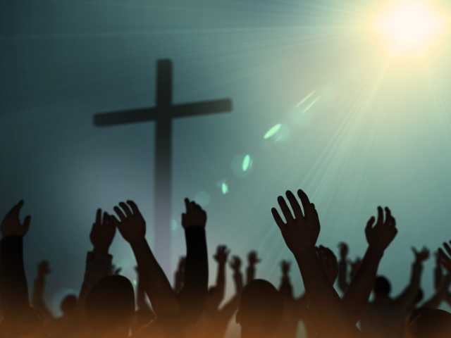 a crowd worshipping God near a cross
