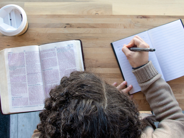 curly haired person taking notes