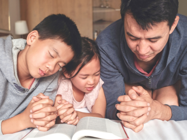 father praying with son and daughter