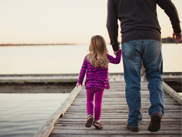 father and daughter walking on pier