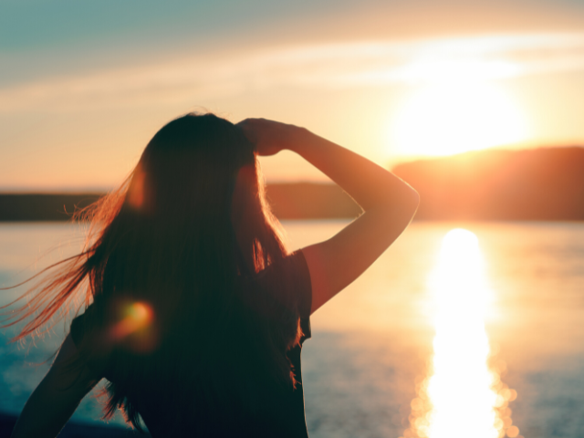 Woman looking at sunrise across a lake