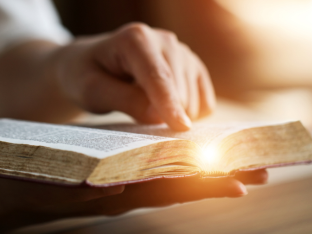 person pointing to a scripture in an open Bible