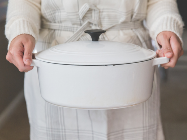 person carrying a large covered pot of food