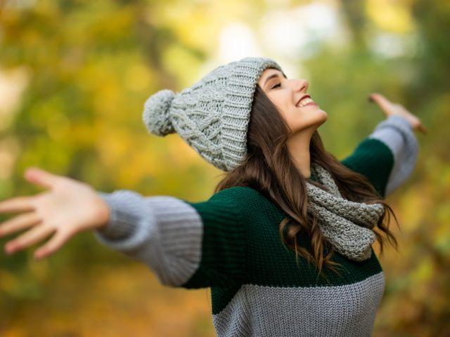 woman with arms extended in fall season