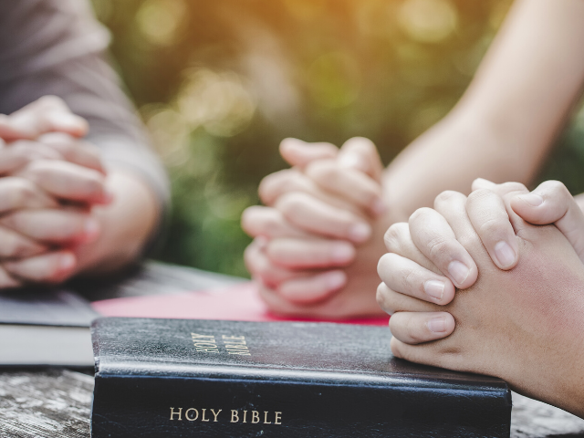 group praying with their Bibles on the table