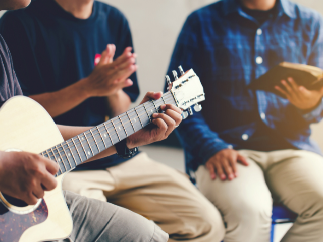 man playing guitar and man with open Bible in small group