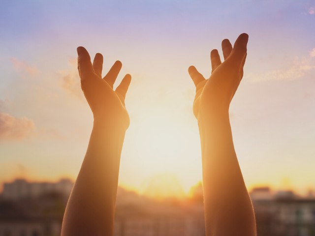 hands raised to the sunrise