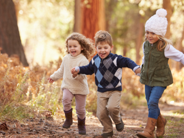 happy children holding hands on a nature path in autumn