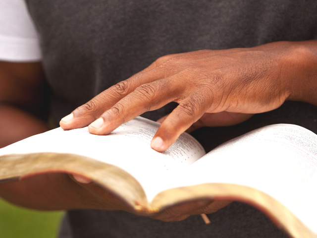 hand holding an open Bible