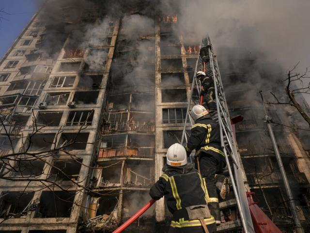 Firefighters climb a ladder while working to extinguish a blaze in a destroyed apartment building after a bombing in a residential area in Kyiv, Ukraine, Tuesday, March 15, 2022 (AP Photo/Vadim Ghirda)