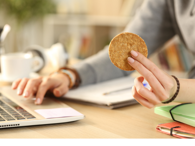 girl holding a cookie while using her laptop