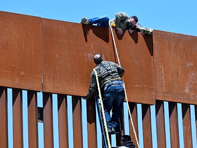 Migrants scale border fence at the US/Mexico border in Tecate, Mexico, using ladders and ropes, April 21, 2022. (AP Photo/Denis Poroy)