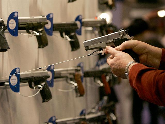 A participant at an NRA Convention holds one of the handguns at a manufacturer&#039;s booth. (Image credit: National Rifle Association)
