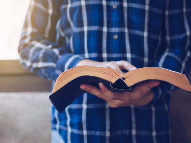 holding and reading open Bible