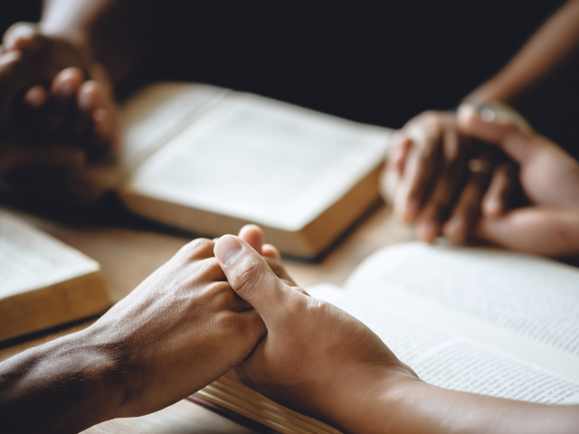 small group of people studying the Bible and holding hands