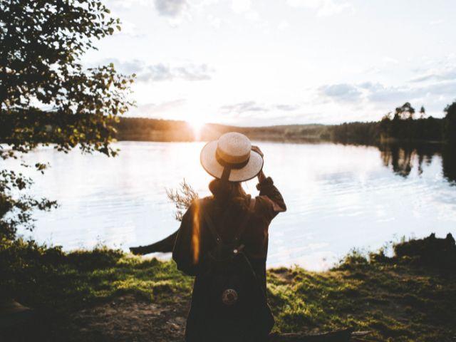 woman in hat looking at sunset