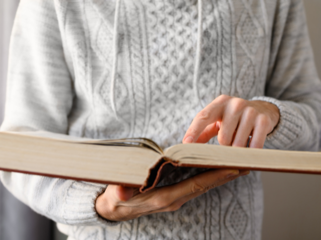person pointing to a page in an open book