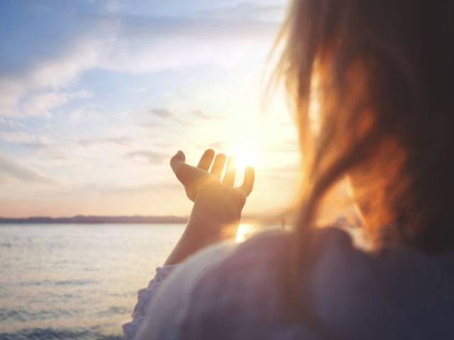 person praising God beside a lake with hands lifted