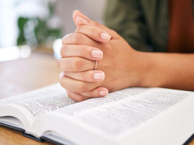 hands crossed on bible in prayer