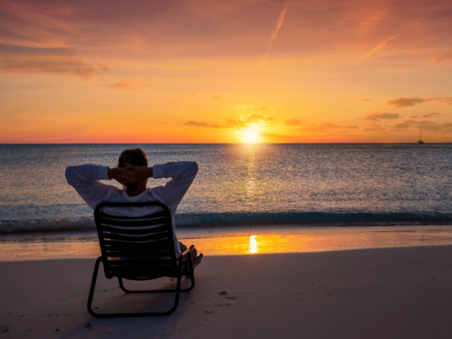man sitting in a beach chair by the ocean watching the sunrise