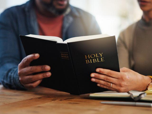 two people reading an open Bible