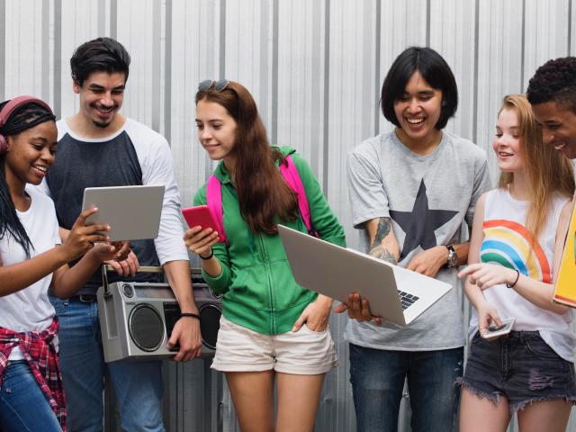 Group of teens hanging out sharing technology