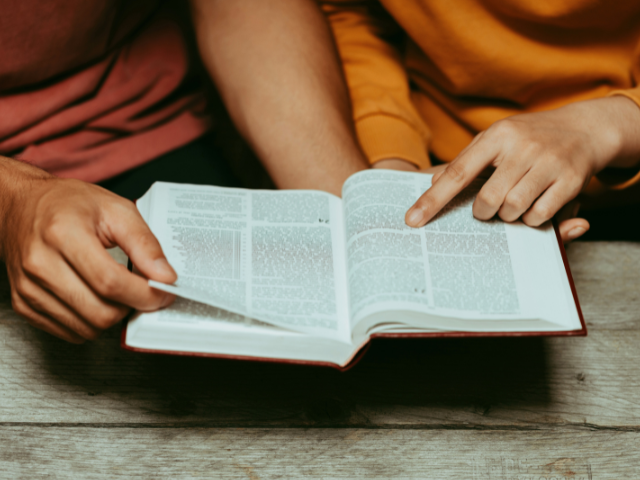 two people reading the Bible and pointing at Scripture