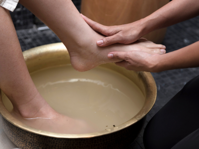 one person washing another person&#039;s feet in a big bowl